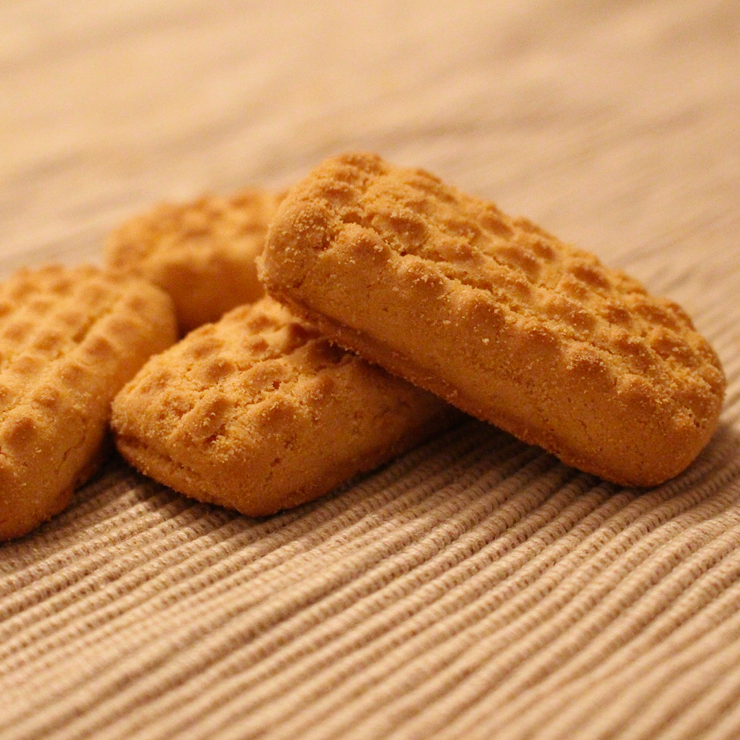 Biscoitos caseiros crocantes de textura rústica, dourados e servidos sobre superfície de tecido.